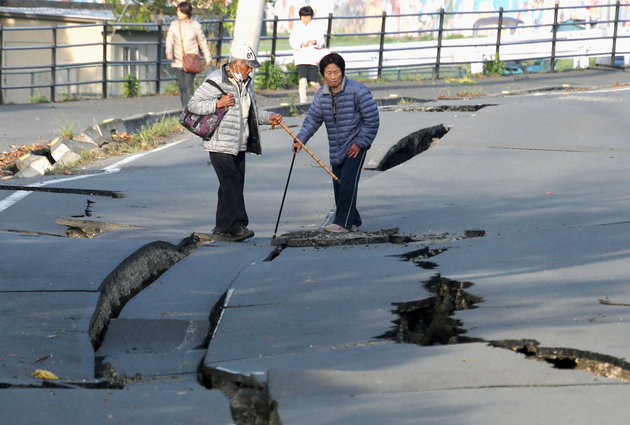 Local residents look at cracks caused by an earthquake on a road in Mashiki town, Kumamoto prefecture, southern Japan, in this photo taken by Kyodo April 16, 2016. Mandatory credit REUTERS/Kyodo ATTENTION EDITORS - FOR EDITORIAL USE ONLY. NOT FOR SALE FOR MARKETING OR ADVERTISING CAMPAIGNS. MANDATORY CREDIT. JAPAN OUT. NO COMMERCIAL OR EDITORIAL SALES IN JAPAN. THIS IMAGE WAS PROCESSED BY REUTERS TO ENHANCE QUALITY, AN UNPROCESSED VERSION WILL BE PROVIDED SEPARATELY.
