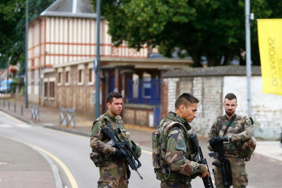 French soldiers stand guard at the scene of an attack that left a priest dead in Saint Etienne du Rouvray, Normandy, France on Tuesday. Photo Credit: US News